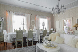 White coffee table and sofa with scatter cushions in front of long dining table with chairs