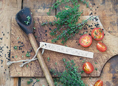 Thyme and tomatoes with a wooden spoon on a wooden board