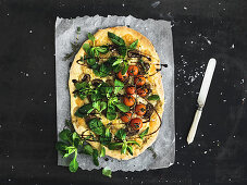 Rustic homemade pizza with fresh lamb's lettuce, mushrooms and cherry-tomatoes