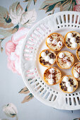 Mini tarts filled with cream, meringue, chocolate chips and cocoa (top view)