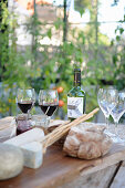 A table laid with cheese, bread and wine in a garden