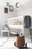 Soft toys in basket on wheels, white child's chair and cot