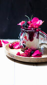 Semolina pudding with jam, berries and rose petals in a flip-top jar