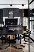 Round, black table with matching chairs in an open kitchen