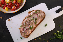 A slice of bread spread with liver pâté and spring onions served with tomato salad