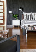 Doppelbett und weißer Nachtkästchen im Schlafzimmer mit schwarzer Tapete