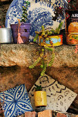 Tiles, succulents and decorative plate on rustic stone shelf