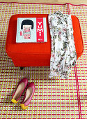 Book and dress on red pouffe and ballet flats on patterned rug