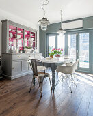 Kitchen dresser with hot-pink cupboard interiors in sunny dining room in shades of grey