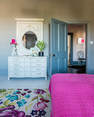 Antique chest of drawers with mirror in bedroom with open door