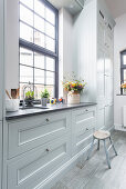 Window in country-house kitchen with pale grey panelled cabinets