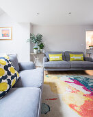 Colourful scatter cushions on grey sofas in simple living room