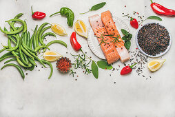 Flat-lay of raw salmon fish fillet steaks with vegetables, greens, rice and spices