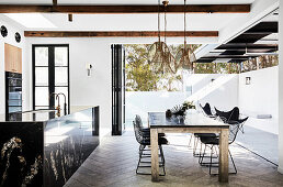 Black granite kitchen island, dining table and classic chairs in open living space