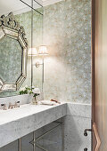 Marmor-Waschtisch und Wandspiegel im Badezimmer mit Tapete