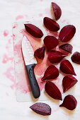 Beetroot cut in wedges with a knife on a chopping board