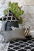Black-and-white rug and cushions in front of leafy branches