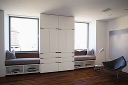 White, floor-to-ceiling wardrobe flanked by window seats fitted in window niches