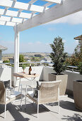 Elegant chairs, table and potted plants on roof terrace