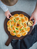 Pull-apart bread filled with ham and cheese on a wooden board (seen from above)