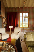 Armchairs and standard lamp in converted loft with tartan wallpaper