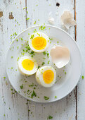 Boiled eggs, halved with parsley sprinkled on a plate (seen from above)