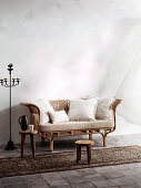 Candlestick next to rattan sofa with pillows and wooden stool