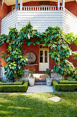 Brick house with balcony over overgrown entrance area