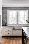 White kitchen unit and gray wall tiles in the kitchen with window