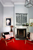 Two chairs on red carpet in front of fireplace in living room with light gray walls and stucco