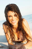 Brünette Frau im pastellrosa Bikini liegt am Meer