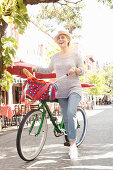A blonde woman wearing jeans and a knitted jumper out shopping on her bike