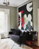 Abstract painting above black velvet sofa in living room