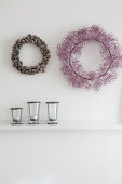 Autumnal wreaths on white wall above candle lanterns on shelf