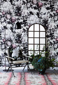 Chair and floor mirror against opulent floral wallpaper