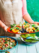 Woman serving Summer salad of peaches and blueberries