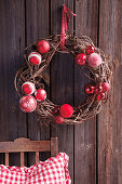 Festive wreath of willow and red baubles hung on wall