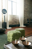 Light bulbs in bowls on coffee table in front of two furry pouffes