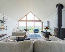 Pale seating and log burner in elegant living room with glass wall