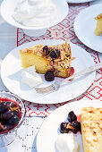 Ein Stück Mandel-Karamellkuchen mit eingelegten Kirschen mit Sahne