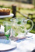 Ice water with lemon and mint in glass carafe and jar
