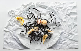 Food-Art: Schwarze Linguine mit Oktopus auf zerknittertem Papier