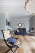 Chair with woven seat and backrest, coffee table and chaise longue in front of fireplace