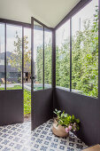 Glazed area with cement floor tiles and French windows leading into garden