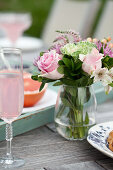 Brunch outside, flowers, glasses of sparkling pink lemonade, grapefruit halves on an outdoor table