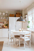 Round dining table and chairs in white, rustic kitchen