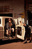 Junge Frau mit Hut im Pickup sitzend, Freundin an der Autotür stehend
