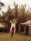 A blonde woman wearing a hat, a rust-coloured skirt and a coat