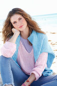 Junge Frau in lila T-Shirt, rosa Pullover und blauer Pullover über den Schultern