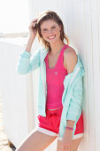 Junge Frau in pinkfarbenem Top, Jacke und Shorts am Strand